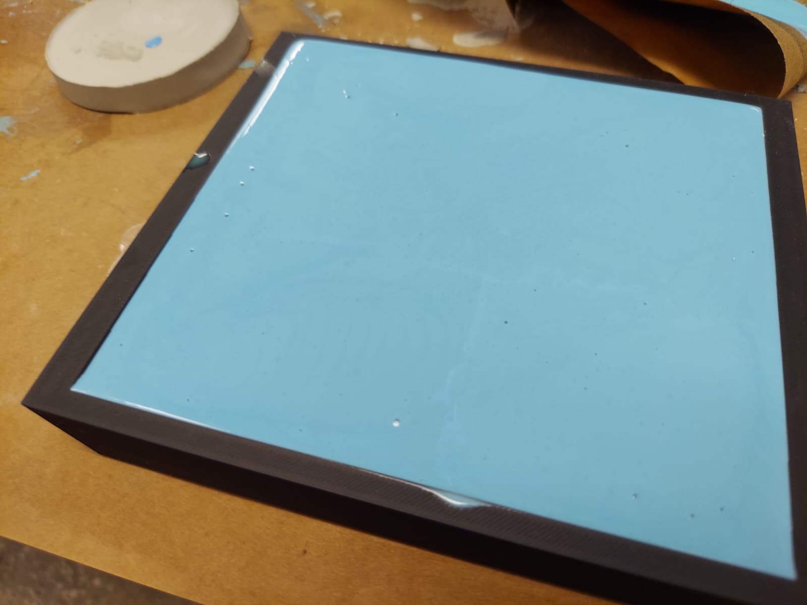 Blue silicone being poured into tangram frame